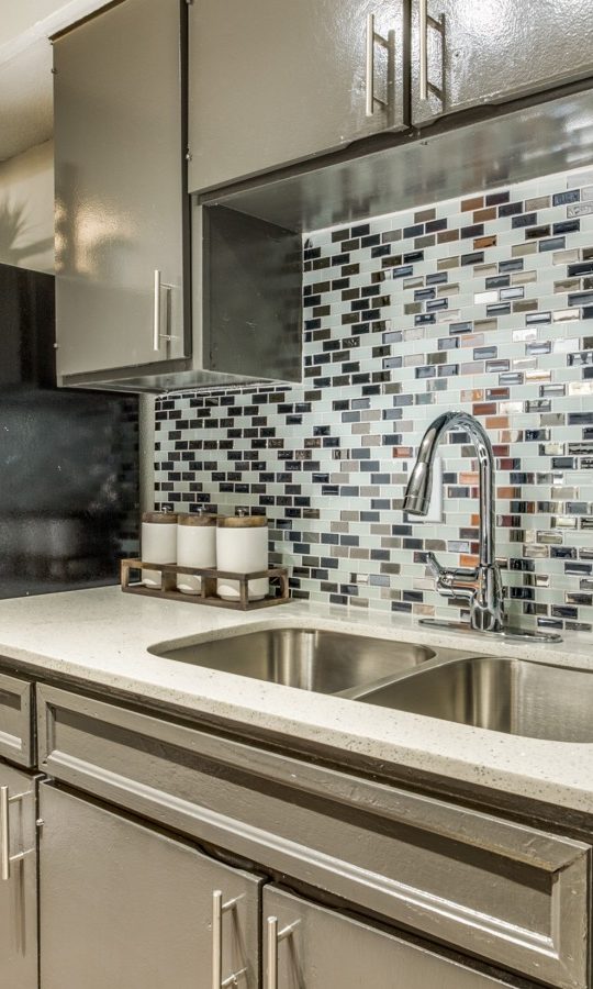 a kitchen with stainless steel appliances and tile backsplash at The Zeke